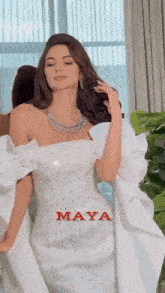 a woman in a white dress with the name maya on the bottom right