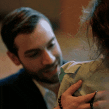 a man in a suit is touching the back of a woman 's shoulder