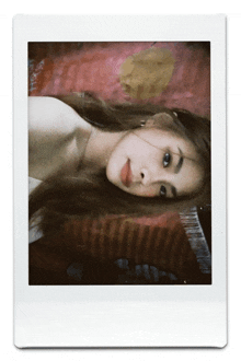 a polaroid picture of a woman laying on a bed with a pink blanket behind her