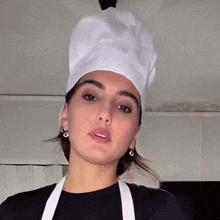 a woman wearing a chef 's hat and apron making a face