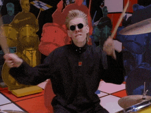 a man wearing sunglasses is playing the drums in front of a drum set