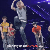 a man in a gray shirt is dancing on a stage with two other men