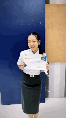 a woman in a white shirt and black skirt holds a certificate