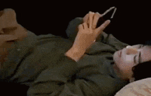 a man is laying on his stomach on a bed looking at his cell phone .