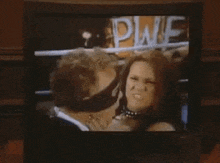 a man and a woman are kissing in front of a pwe sign