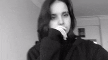 a black and white photo of a woman taking a selfie with her hand on her chin .