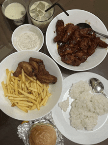 a table topped with plates of food including chicken wings and french fries