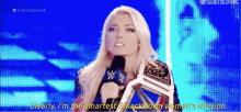 a woman is holding a microphone and a wrestling championship belt .