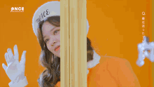 a woman wearing an orange jacket and a white hat that says twice