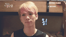 a young man with pink hair is standing in front of a mbc music advertisement