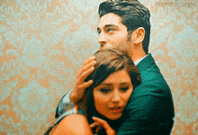 a man in a suit is hugging a woman