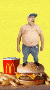 a shirtless man standing on top of a mcdonalds hamburger