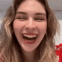 a close up of a woman laughing with her eyes closed .