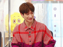 a man in a plaid shirt is smiling in front of a yellow stuffed animal