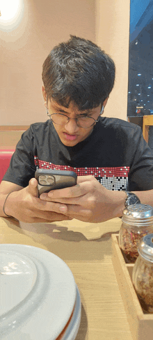 a boy wearing glasses is looking at his phone
