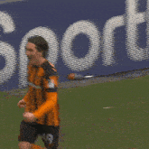 a soccer player wearing an orange and black striped jersey is celebrating a goal