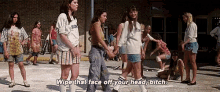 a group of girls are walking down a sidewalk and one of them is saying `` wipe that face off your head bitch ''