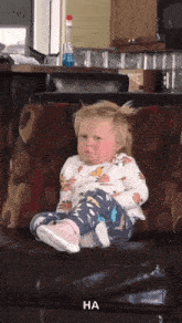 a little girl is sitting on a couch and making a funny face with ha written below her