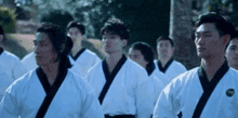 a group of young men in karate uniforms are standing in a row .