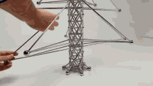 a person is playing with a tower made of metal balls