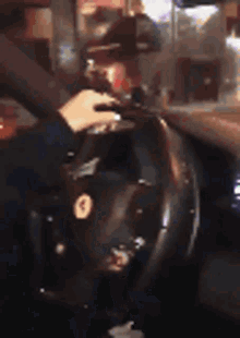 a person is driving a car and holding the steering wheel in a blurry photo .