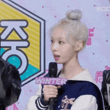 a woman is holding a microphone in front of a sign that says kic
