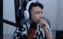 a man wearing headphones is sitting in front of a microphone and talking into it .
