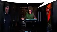 a man is sitting at a keyboard in front of a sign that says " celebrate "