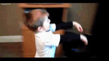a young boy is playing with a remote control in front of a tv ..