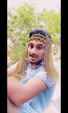 a man wearing a turban and a nose ring is standing in front of trees .