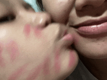 two women are kissing with lipstick on their faces