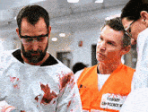 a man wearing an orange vest that says " emergency " on it