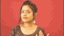a woman with a bindi on her forehead is touching her hair and smiling .