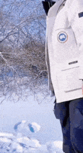 a person wearing a white jacket and blue pants is standing in the snow .