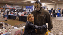 a woman hugging a jason voorhees statue at a convention
