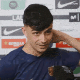 a young man in a blue shirt is talking to a microphone .