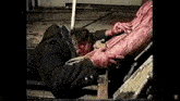 a man with blood on his face is laying on a wooden plank with a bloody leg .