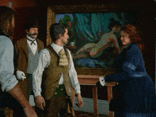 a group of people are standing around a naked woman painting