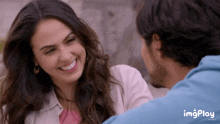 a man and a woman are looking at each other and the woman is smiling and the man is wearing a blue hoodie