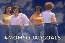 a group of women are standing next to each other in front of a cloudy sky .
