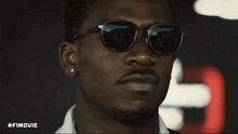 a close up of a man wearing sunglasses with #fimovie written below him