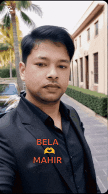 a man in a suit and black shirt has the name bela mahir on his shirt
