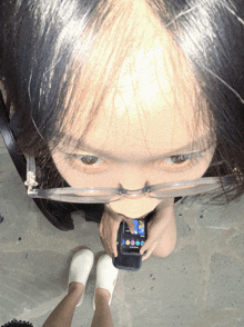 a woman wearing glasses is holding a cell phone with a screen that says ' google play ' on it