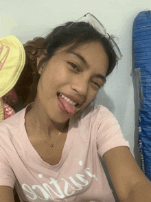 a woman wearing a pink shirt that says ' mitzui ' sticking her tongue out