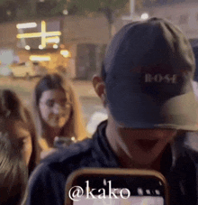 a man wearing a bose hat holds a cell phone in front of his face