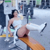 a woman is sitting on a bench in a gym with her legs up .
