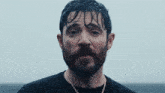 a man with a beard wearing a black shirt and a gold chain
