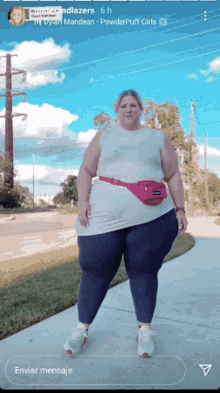 a woman is standing on a sidewalk with a pink fanny pack on her waist
