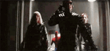a group of superheros are walking through a dark hallway .