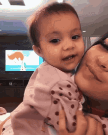 a baby is being held by a woman in front of a tv